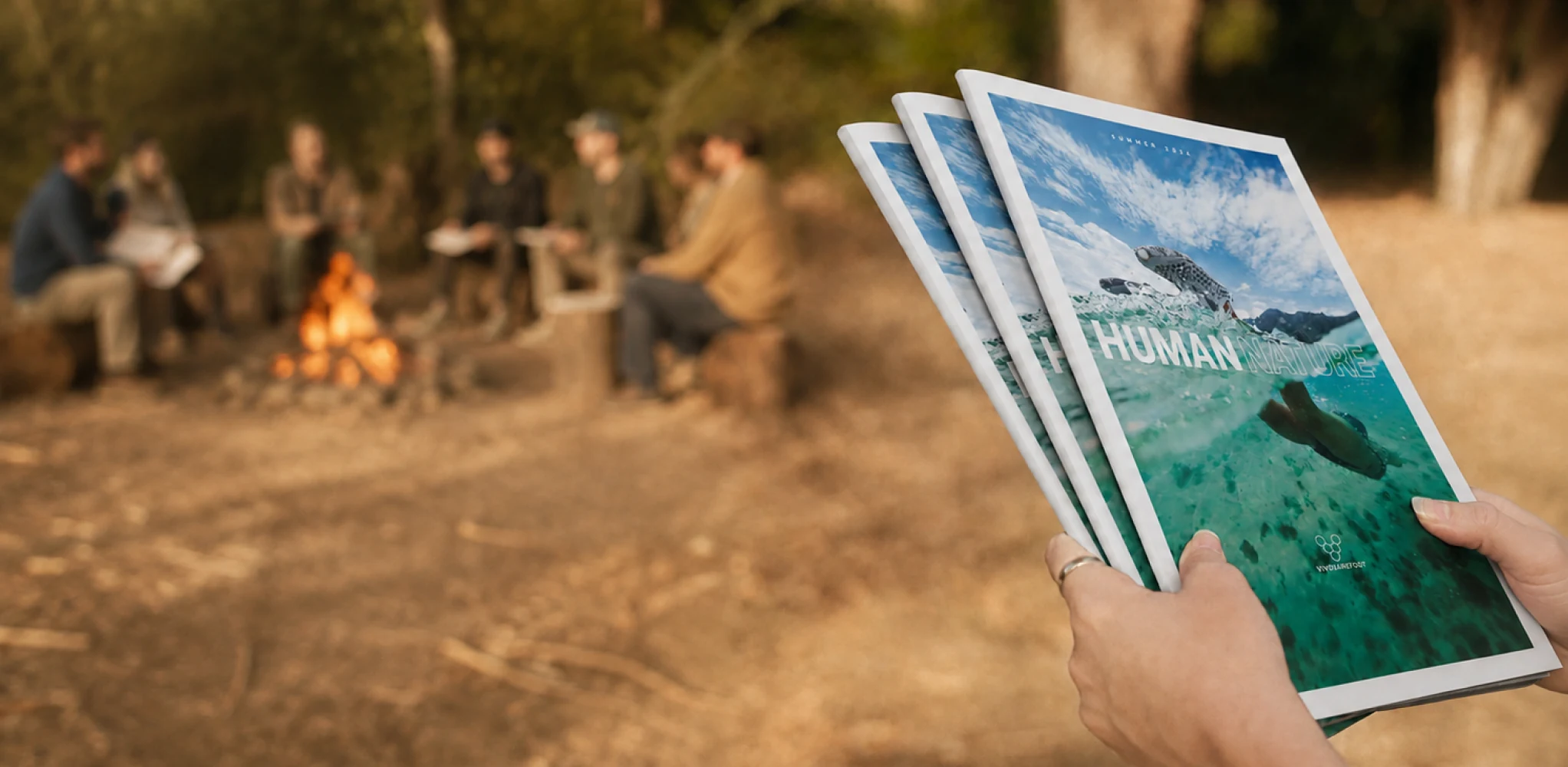 Human Nature catalogues held beside an outdoor campfire